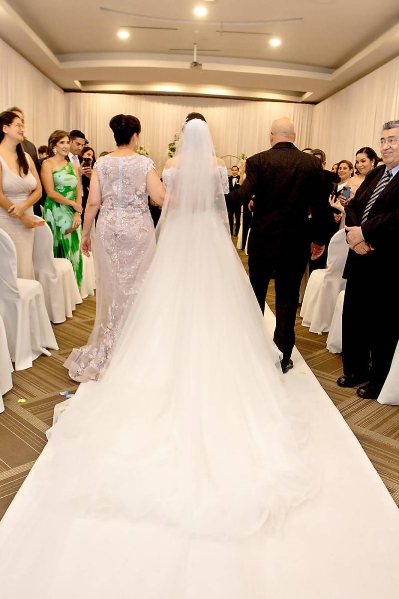 La novia camina rumbo al altar del brazo de sus padres