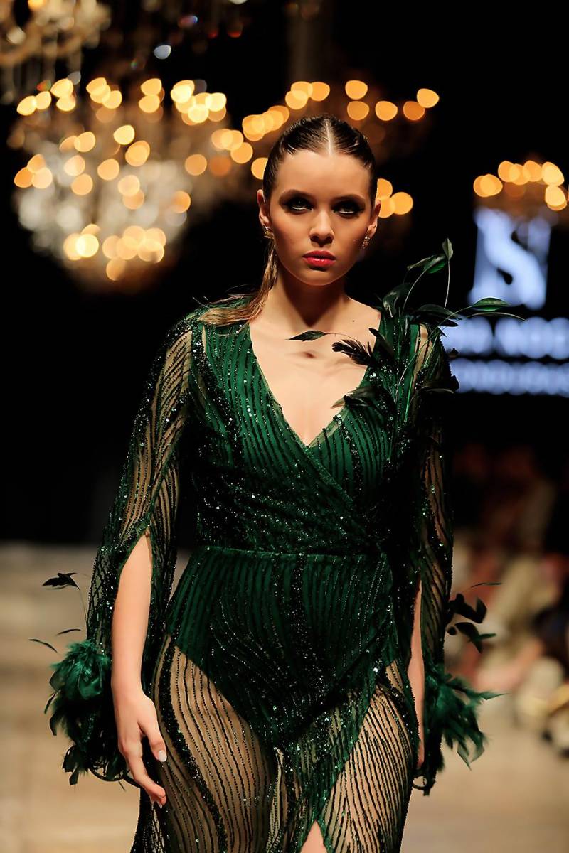 Vestido traslapado en transparencia con aplicaciones de plumas de avestruz en hombros, puños y falda que como explica su autora, “es un tributo a la fuerza, la libertad y la elegancia de la mujer moderna, cuyo espíritu indomable la lleva ac onquistar el mundo con gracia y determinación”.