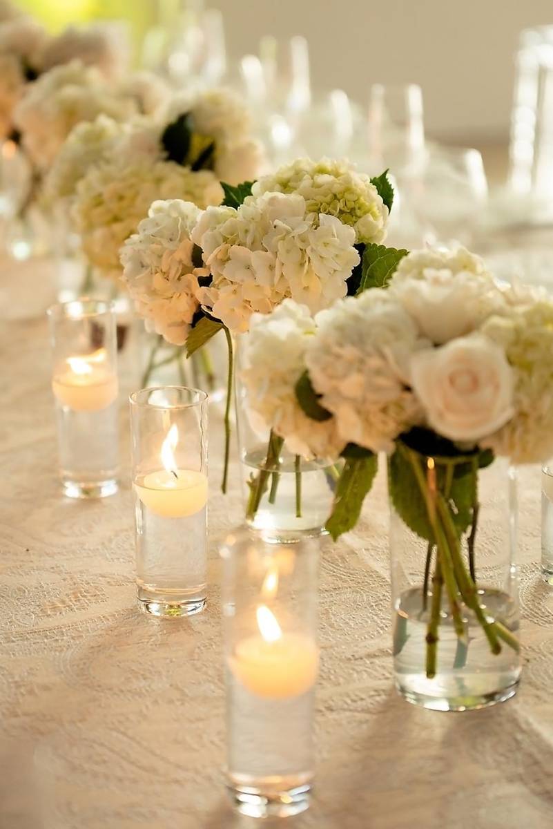 Arreglos con diferentes combinaciones de flores sobre bases critalinas y velas flotantes destacaban en las mesas vestidas con manteles bordados