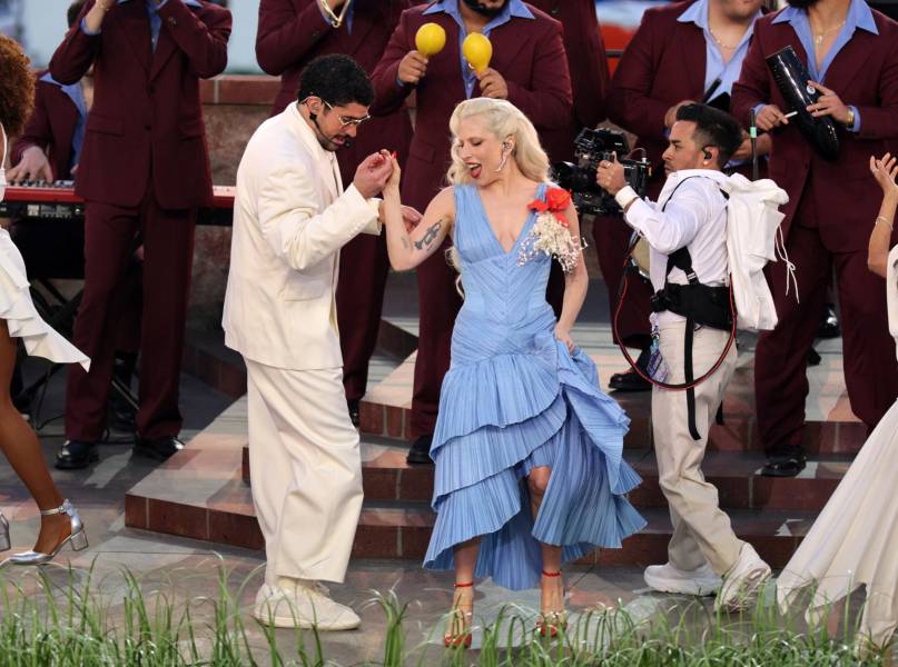 Bad Bunny junto a la cantante estadounidense Lady Gaga, quien lució en el show del medio tiempo del Super Bowl un diseño del dominicano Raúl López, drapeado en el talle, cuello V y falda en vuelos que contrastaban con sus zapatos y manicura roja y su broche de flor de maga