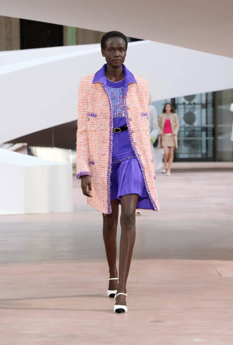 Luego viene un abrigo rosa anaranjado sobre un vestido de jacquardvioleta y un traje de vestir en tonos mimosa con volantes rosa pálido. Los zapatos de tiras siguen la misma lógica.Planos o de tacón, sus colores van desde el azul cielo y el violeta hasta el blanco y el crema.