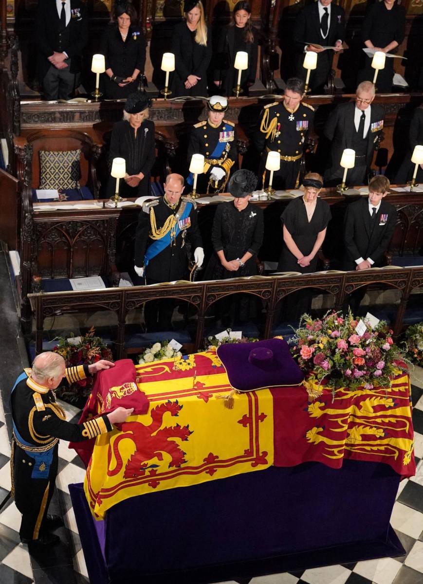 El rey Carlos III coloca la bandera de la compañía de la reina encima del ataúd minutos antes que el ataúd fuera bajado a la cripta (Photo by Jonathan Brady / POOL / AFP)