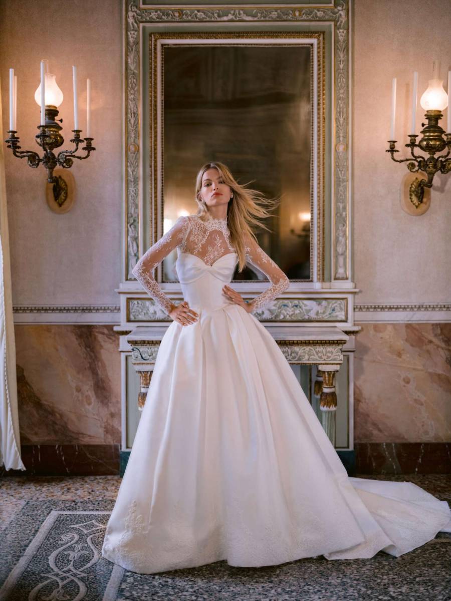 Vestido palabra de honor en mikado, cintura vasca y detalle de encaje , combinado con una chaqueta de manga larga con cuello alto y encaje Chantilly.