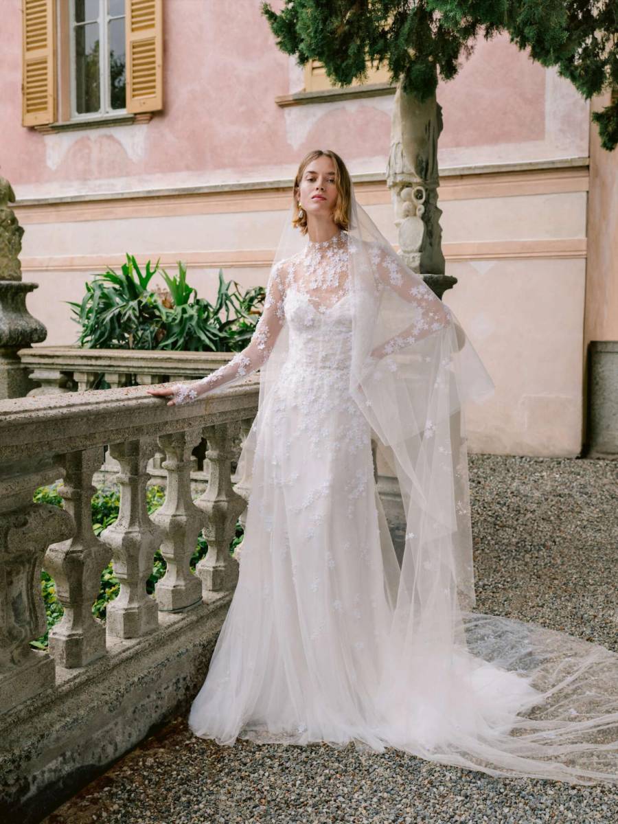 Vestido de fiesta con cuerpo estilo corsé, palabra de honor, de tul floral bordado y falda tubo. Combinado con una chaqueta de tul bordada de manga larga. Con un velo de dos niveles a juego con flores dispersas.