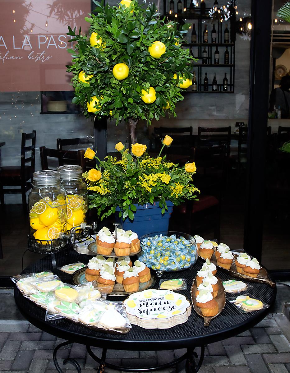Estación de postres adornada con arreglos masivos de rosas, margaritas, solidago en tono amarillo con ramas de limonario.