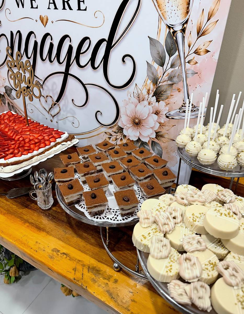 Estación de postres con el fondo que dice “We are engaged”.
