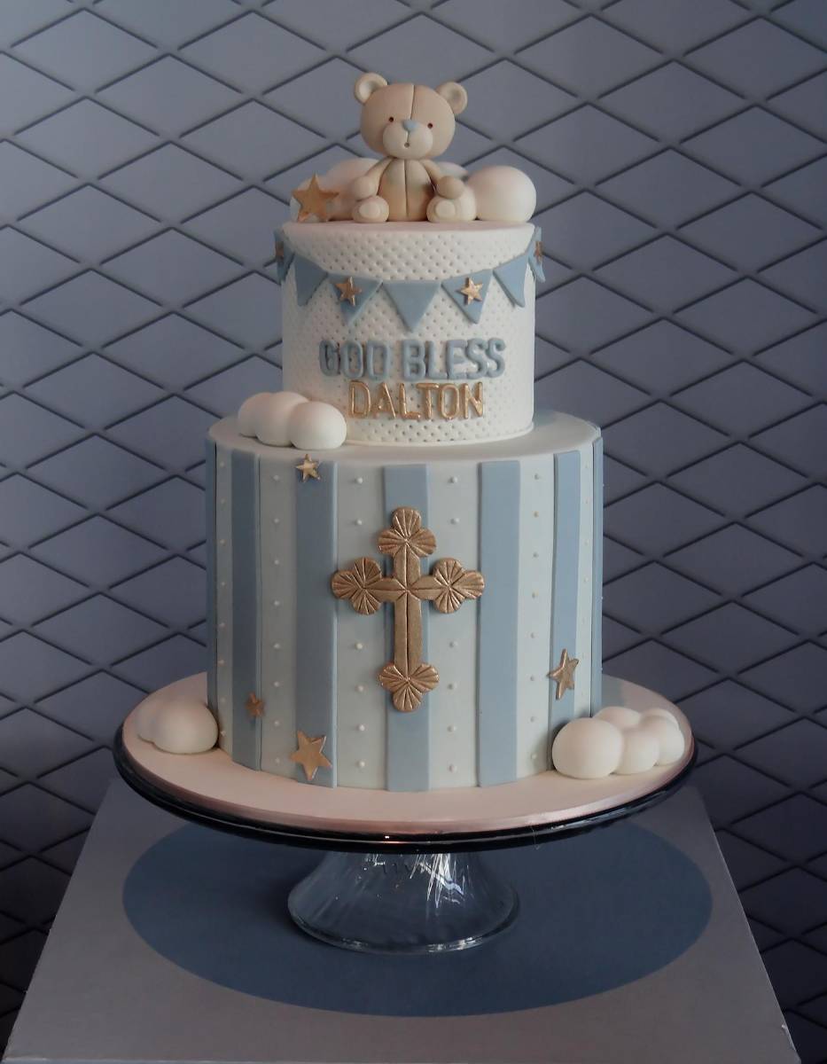 Pastel de dos niveles decorado con una figura de oso y una hermosa cruz.