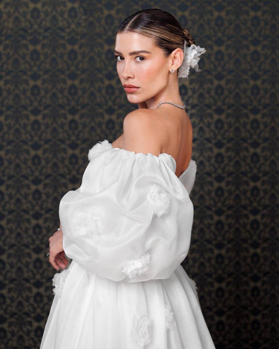 Este segundo vestido de novia se complementa con una falda larga adornada con delicadas flores blancas bordadas, que también se encuentran en la parte superior del conjunto.