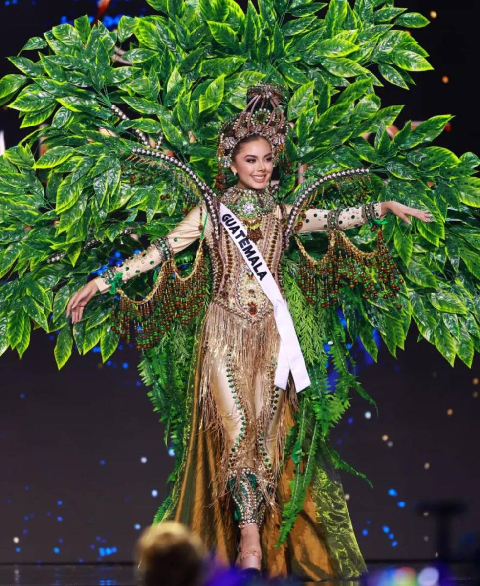 Ana Gabriela Villanueva, Miss Universo Guatemala 2024, deslumbró en la competencia preliminar con su traje nacional «Quauhtlemallan, Pulmón del Mundo». Inspirado en la rica vegetación de Guatemala, el diseño, adornado con lentejuelas, hojas artificiales y pedrería en tonos dorados, cafés y verdes, evocó los exuberantes paisajes y bosques del país.